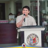 Lalaking nagsasalita sa mikropono sa podium ng Office of the Mayor, Naic, Cavite, sa flag raising ceremony