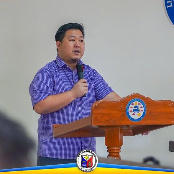 Lalaking nagsasalita sa mikropono sa podium habang nagpupulong sa ABC Hall, Naic